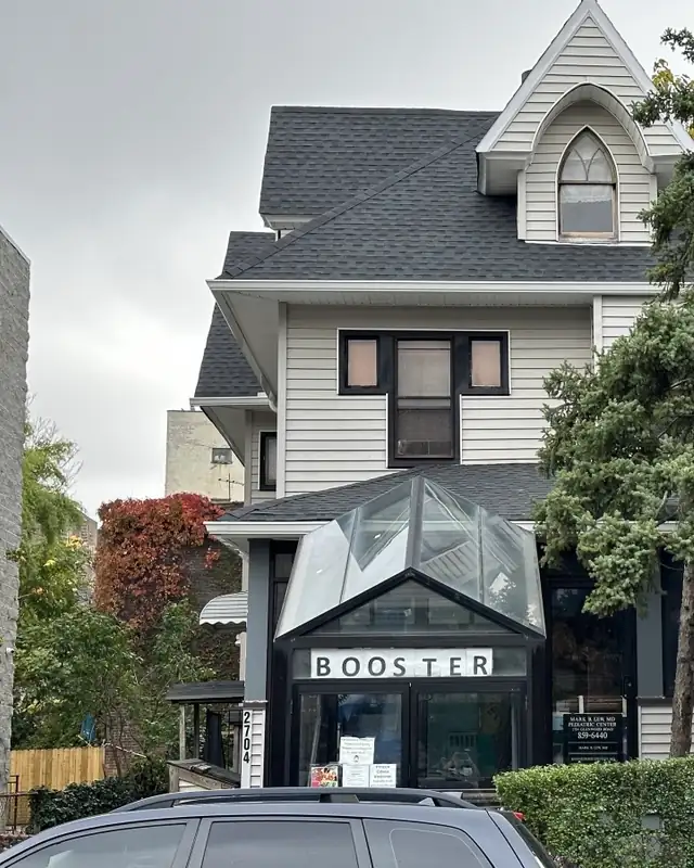 Victorian house with a new gray shingle roof and glass entry canopy