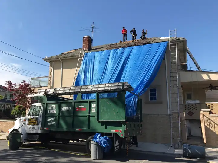 Crew tearing off a roof with a dump truck at the curb