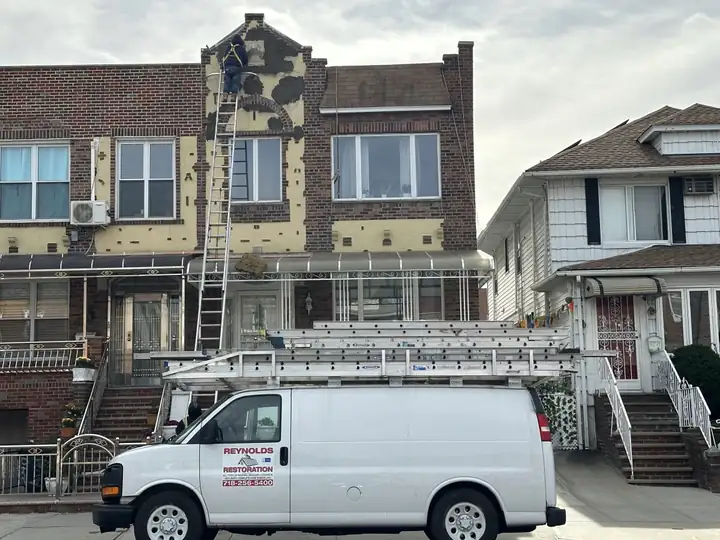 Work van with ladders parked outside a brick row house
