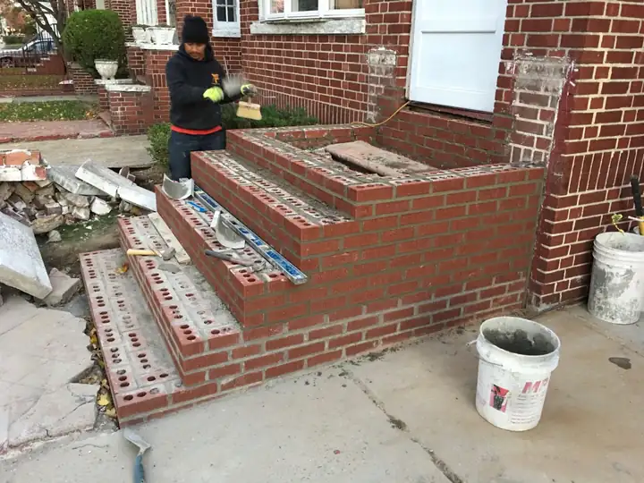 Mason rebuilding red brick front steps