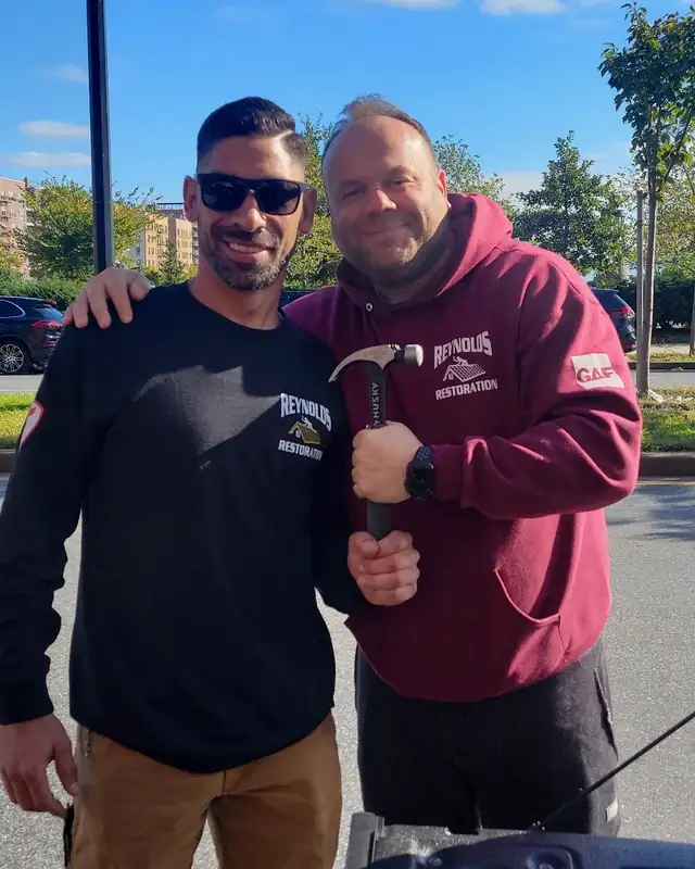 Two members of the Reynolds Restoration team in company shirts, one holding a hammer